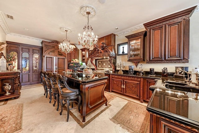 kitchen featuring a notable chandelier, hanging light fixtures, a kitchen island, and crown molding