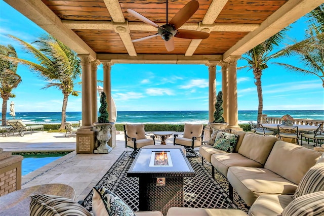 view of patio with a water view, an outdoor living space with a fire pit, and ceiling fan