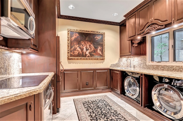 washroom featuring light tile patterned flooring, sink, cabinets, washing machine and dryer, and crown molding