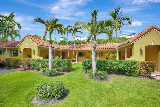 view of front facade with stucco siding, a tiled roof, and a front lawn