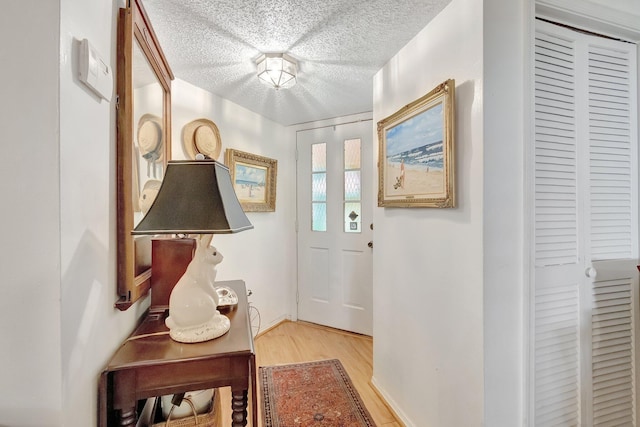 doorway to outside featuring light wood-type flooring and a textured ceiling