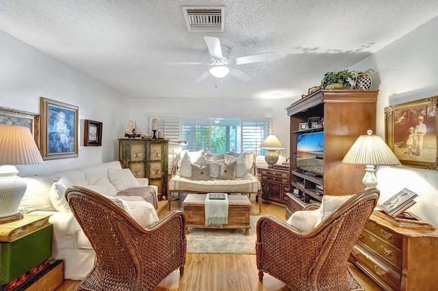 living area featuring a textured ceiling, ceiling fan, and light hardwood / wood-style flooring