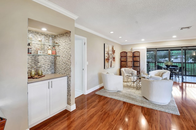 living room featuring a textured ceiling, crown molding, and wood-type flooring