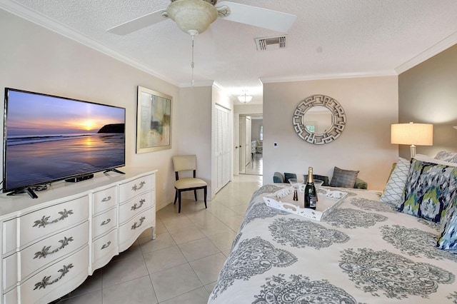 tiled bedroom with a closet, ceiling fan, crown molding, and a textured ceiling