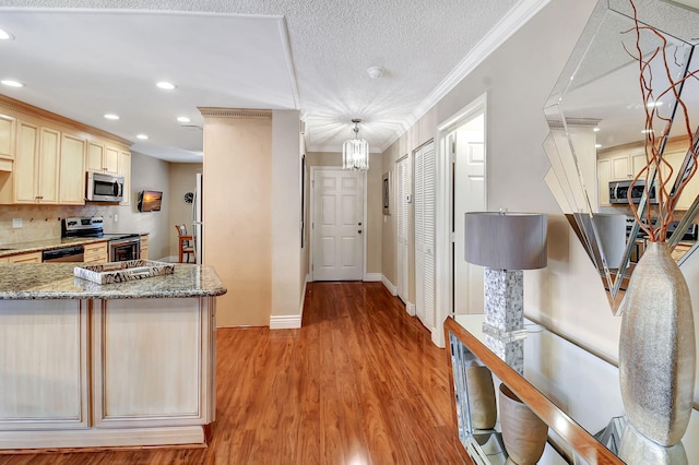 kitchen featuring light wood-type flooring, crown molding, tasteful backsplash, stainless steel appliances, and light stone countertops