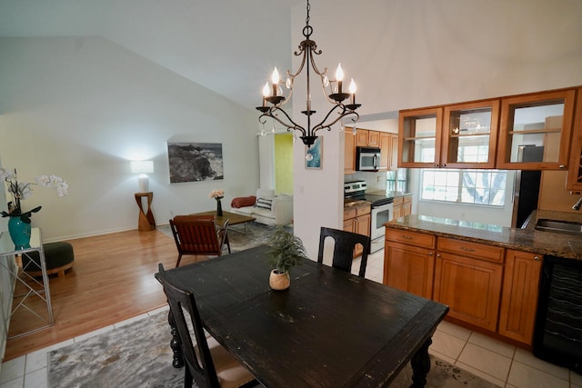 dining space with sink, beverage cooler, light hardwood / wood-style flooring, high vaulted ceiling, and a notable chandelier