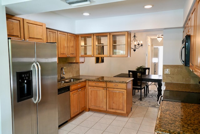 kitchen with light tile patterned flooring, sink, kitchen peninsula, appliances with stainless steel finishes, and dark stone countertops