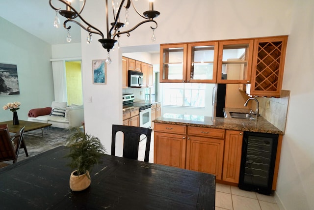 kitchen featuring light stone counters, backsplash, white electric range oven, beverage cooler, and sink