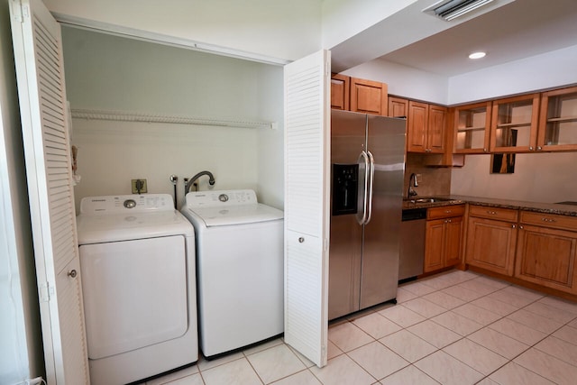 clothes washing area featuring light tile patterned floors, sink, and independent washer and dryer