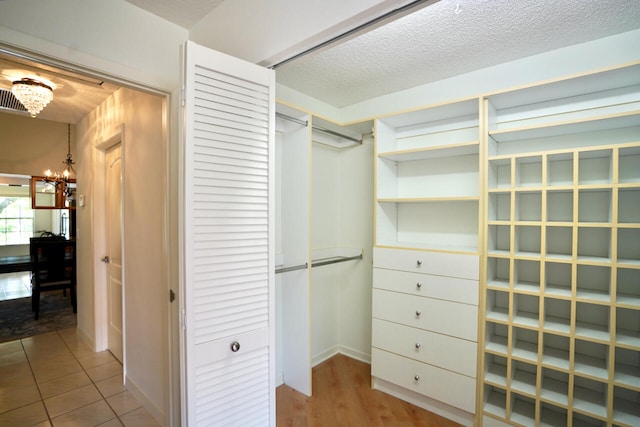 walk in closet featuring a chandelier and light tile patterned floors