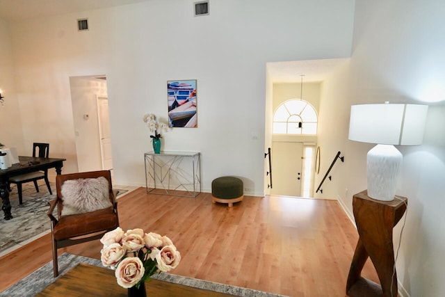 foyer entrance with wood-type flooring and high vaulted ceiling