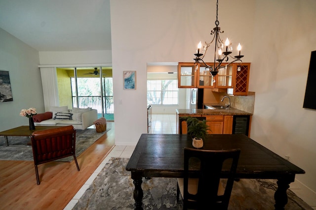 dining room featuring an inviting chandelier, light hardwood / wood-style floors, beverage cooler, and sink