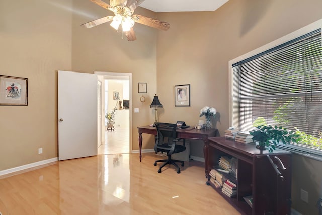 office area featuring a high ceiling, light hardwood / wood-style floors, and ceiling fan