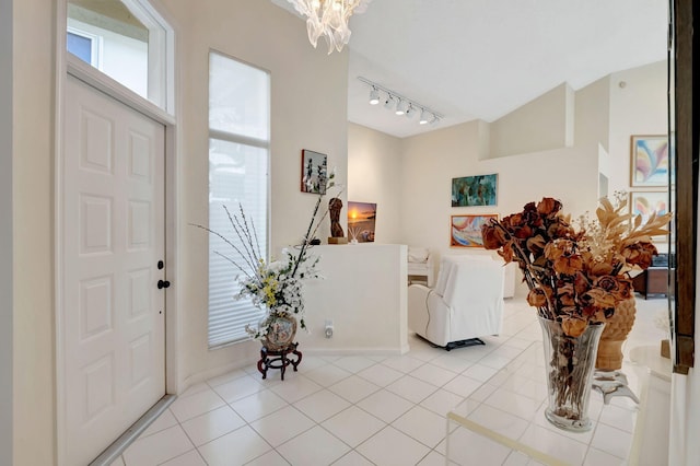 entrance foyer with track lighting, an inviting chandelier, and light tile patterned floors