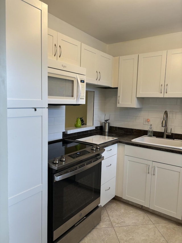 kitchen featuring sink, white cabinetry, stainless steel electric range oven, light tile patterned floors, and backsplash