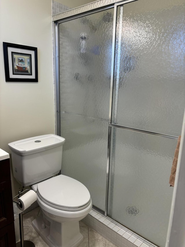 bathroom with tile patterned flooring, vanity, toilet, and a shower with shower door