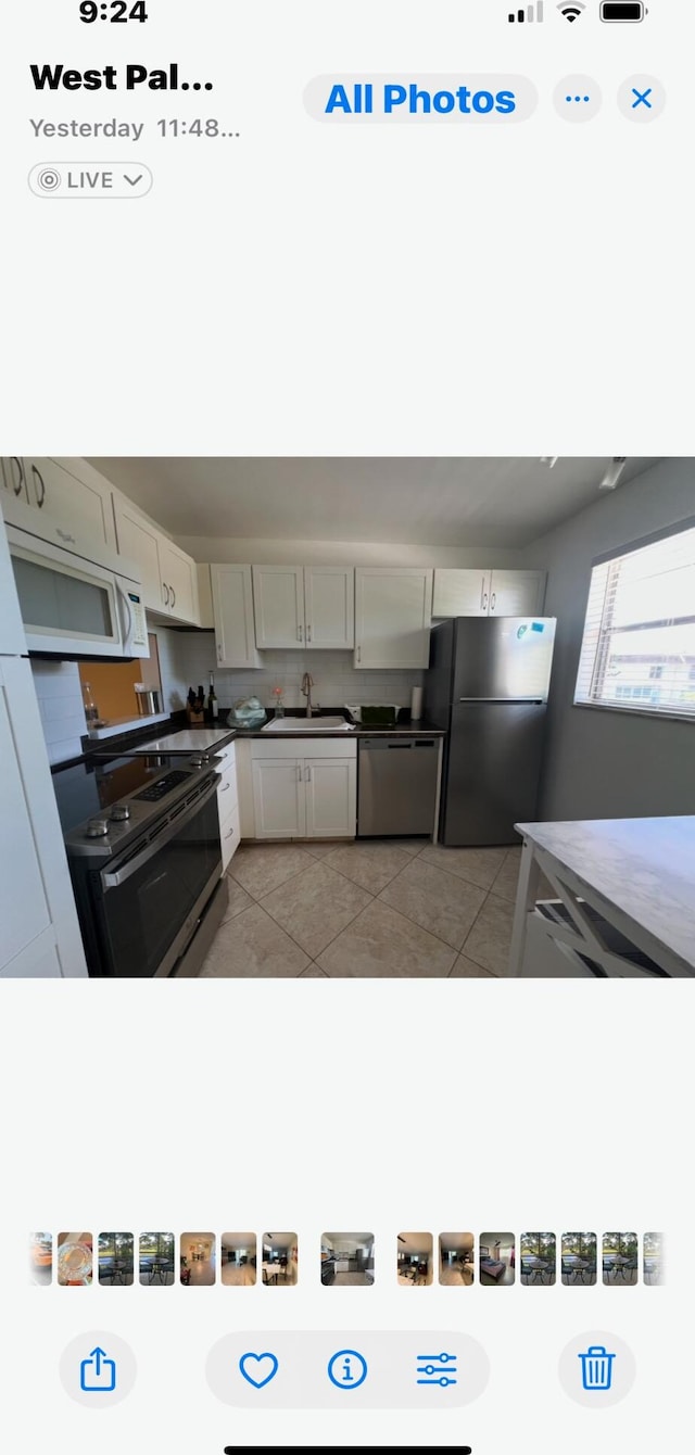 kitchen featuring sink, light tile patterned floors, white cabinets, and appliances with stainless steel finishes