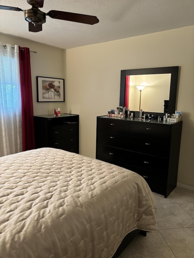 bedroom with a textured ceiling, ceiling fan, and light tile patterned flooring