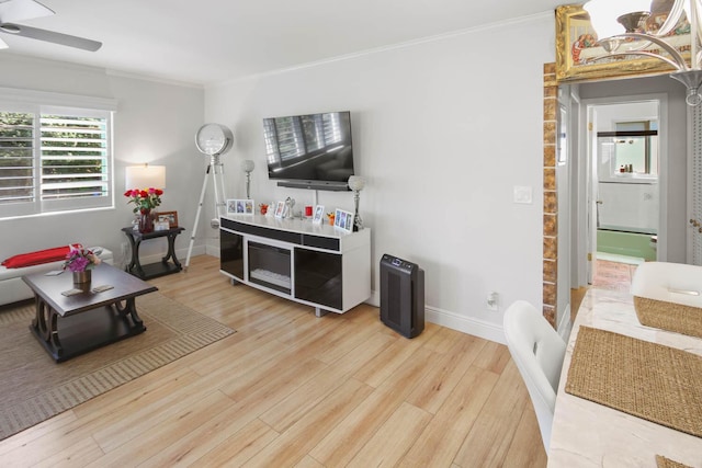 living area with baseboards, wood finished floors, ornamental molding, and a ceiling fan