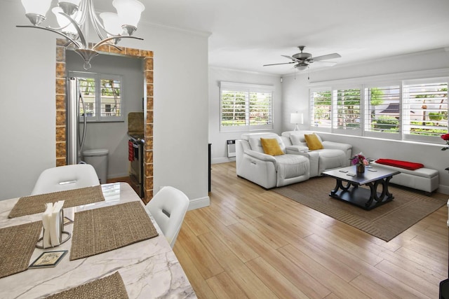 living room featuring ceiling fan, baseboards, light wood-style flooring, and crown molding