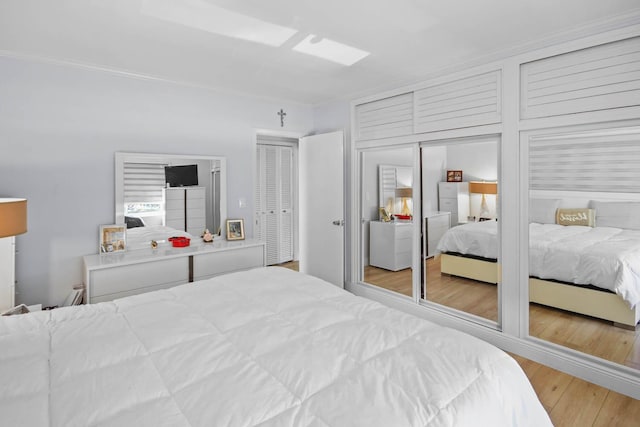 bedroom featuring crown molding, wood finished floors, and multiple closets