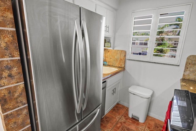 kitchen with tile patterned flooring, baseboards, light countertops, stainless steel appliances, and white cabinetry