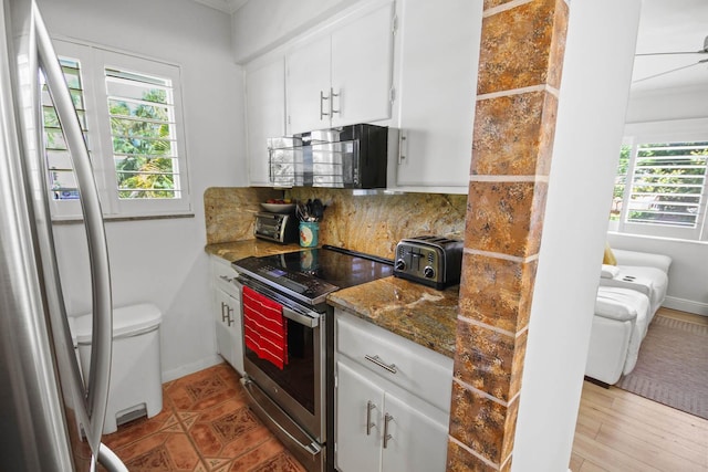 kitchen featuring tasteful backsplash, baseboards, a toaster, stainless steel range with electric stovetop, and white cabinetry