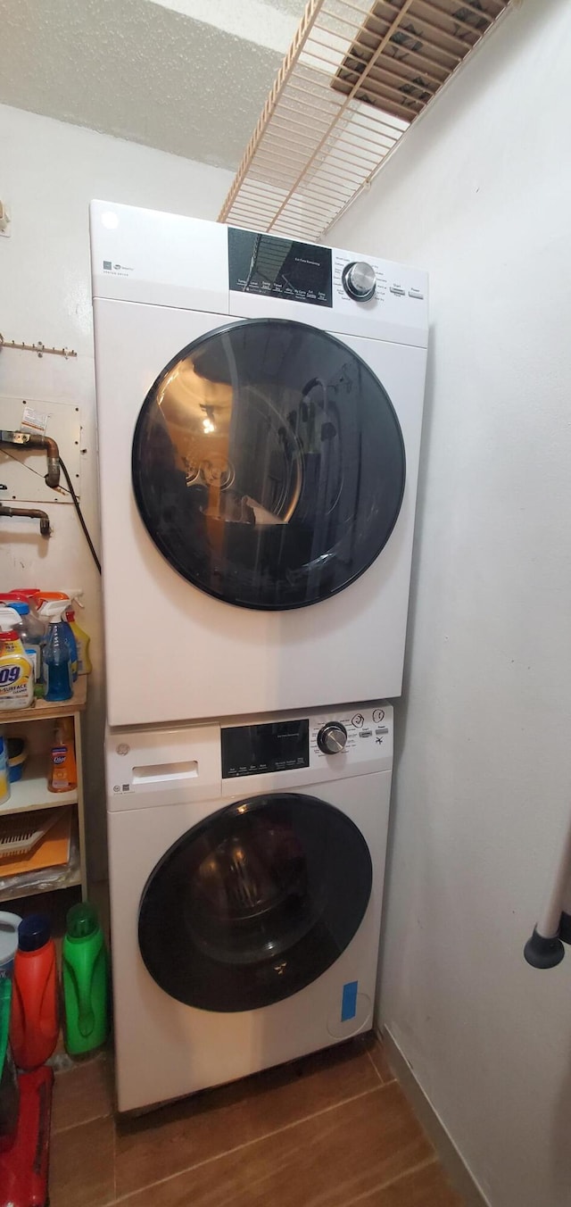 laundry area featuring dark wood-type flooring and stacked washer / dryer