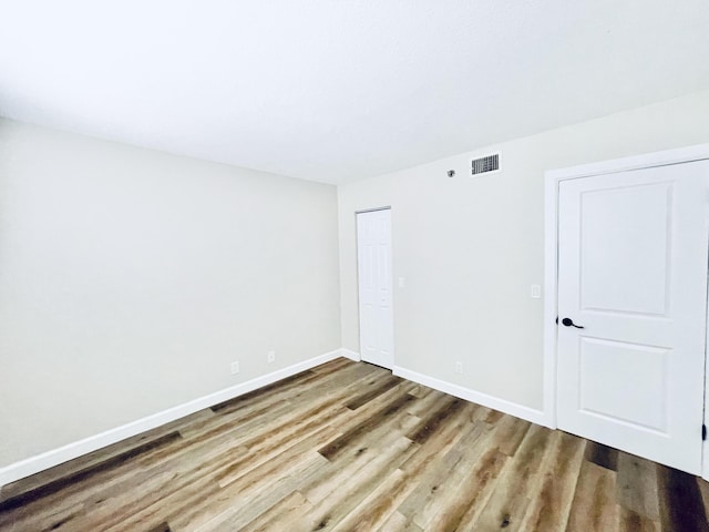 spare room with visible vents, baseboards, and wood finished floors