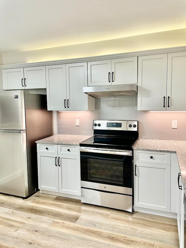 kitchen with light hardwood / wood-style flooring, stainless steel appliances, light stone counters, and tasteful backsplash