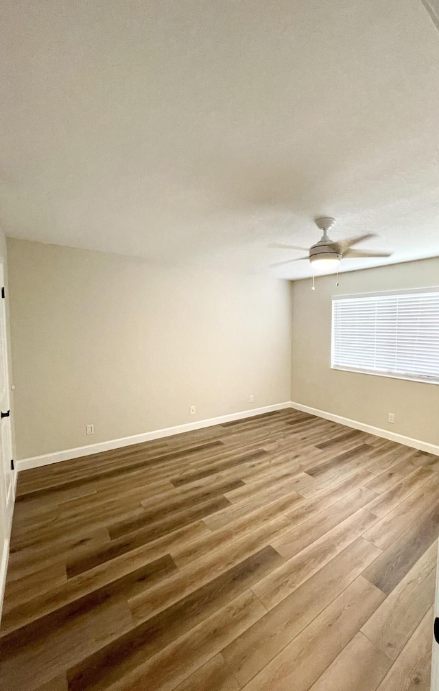 spare room featuring ceiling fan, baseboards, and wood finished floors