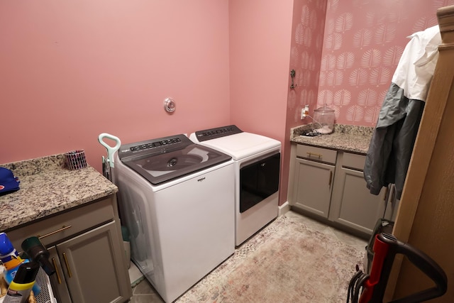 clothes washing area with independent washer and dryer and cabinets