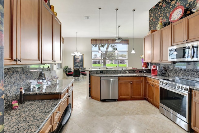 kitchen with stainless steel appliances, sink, kitchen peninsula, pendant lighting, and tasteful backsplash