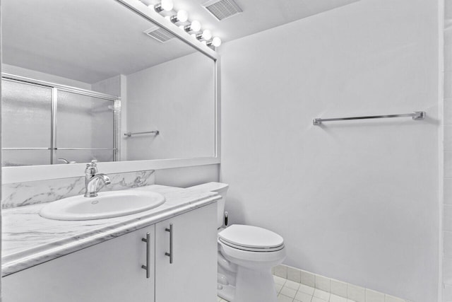 bathroom with vanity, toilet, an enclosed shower, and tile patterned flooring