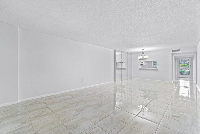 spare room featuring a notable chandelier and a textured ceiling