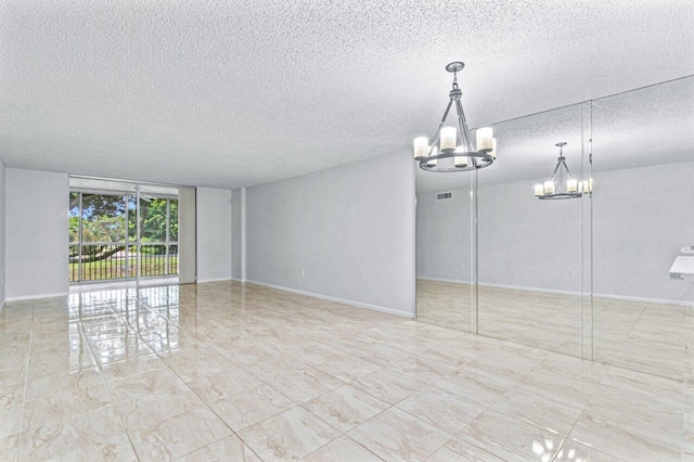 spare room with a chandelier and a textured ceiling