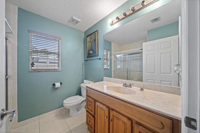 bathroom featuring tile patterned flooring, a textured ceiling, toilet, a shower with shower door, and vanity