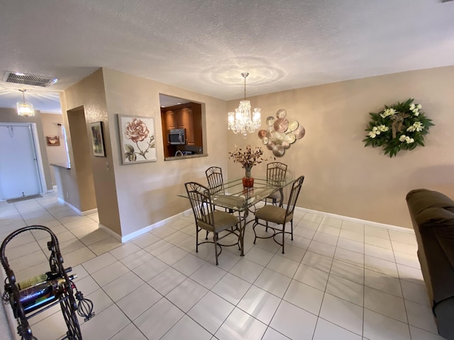 dining area featuring a textured ceiling, an inviting chandelier, and light tile patterned flooring