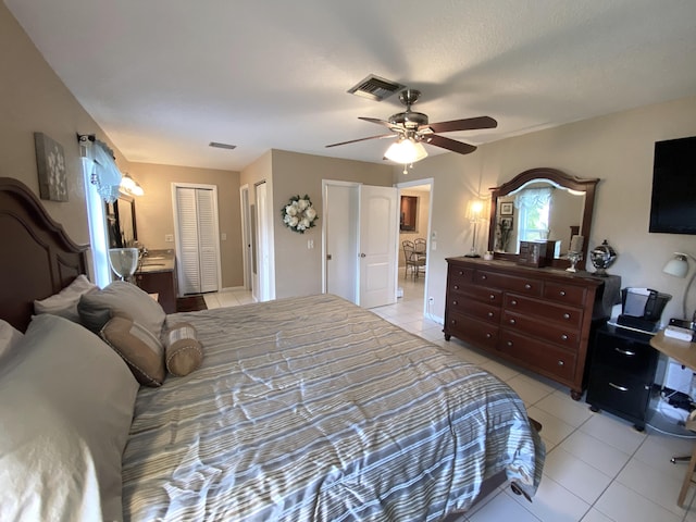 bedroom with a textured ceiling, ceiling fan, and light tile patterned floors