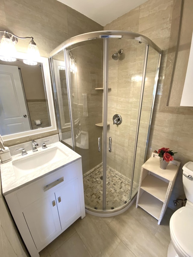 bathroom with tile patterned flooring, an enclosed shower, toilet, tile walls, and vanity