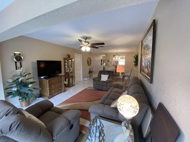 living room featuring ceiling fan with notable chandelier, a textured ceiling, and light tile patterned flooring