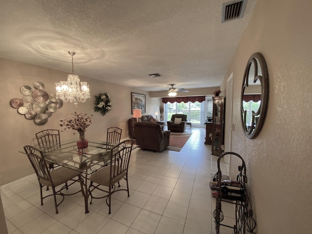 dining area featuring ceiling fan with notable chandelier, a textured ceiling, and light tile patterned floors