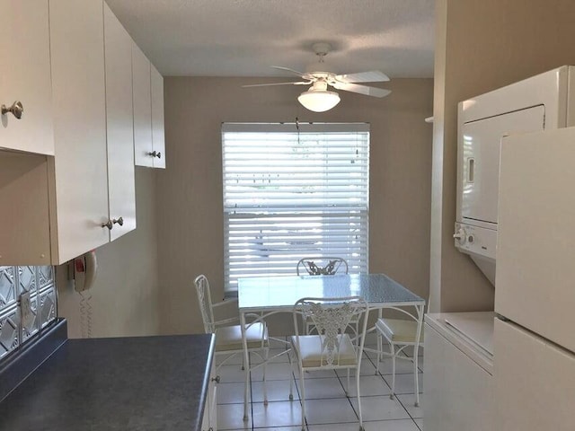 tiled dining room with ceiling fan and stacked washer / dryer