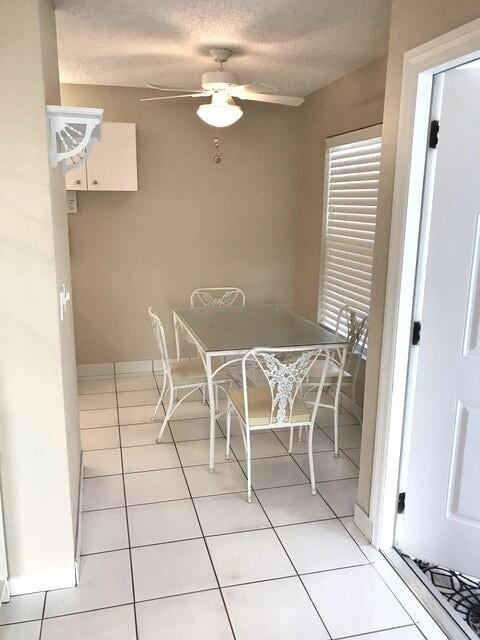 unfurnished dining area with ceiling fan, light tile patterned floors, and a textured ceiling