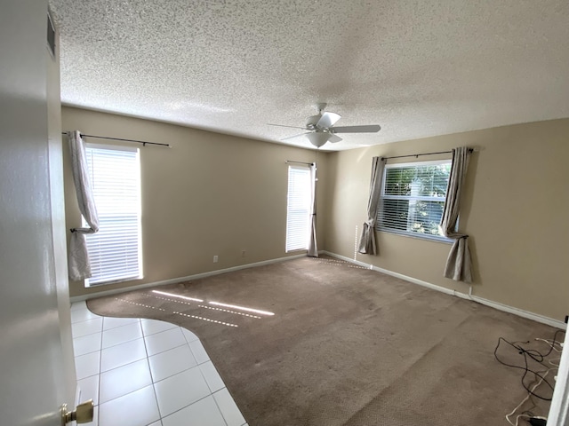 empty room with carpet, a textured ceiling, a wealth of natural light, and ceiling fan