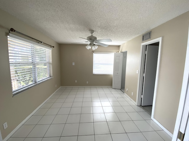 unfurnished bedroom featuring ceiling fan, light tile patterned floors, and a textured ceiling