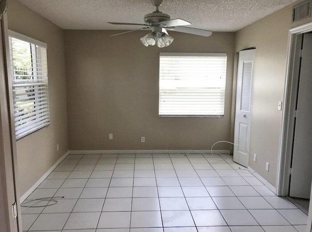 interior space featuring ceiling fan, light tile patterned floors, and a textured ceiling