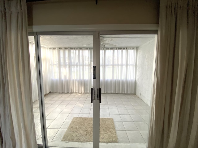 doorway with ceiling fan and light tile patterned flooring