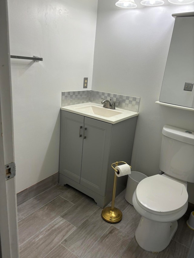 bathroom with vanity, toilet, and decorative backsplash