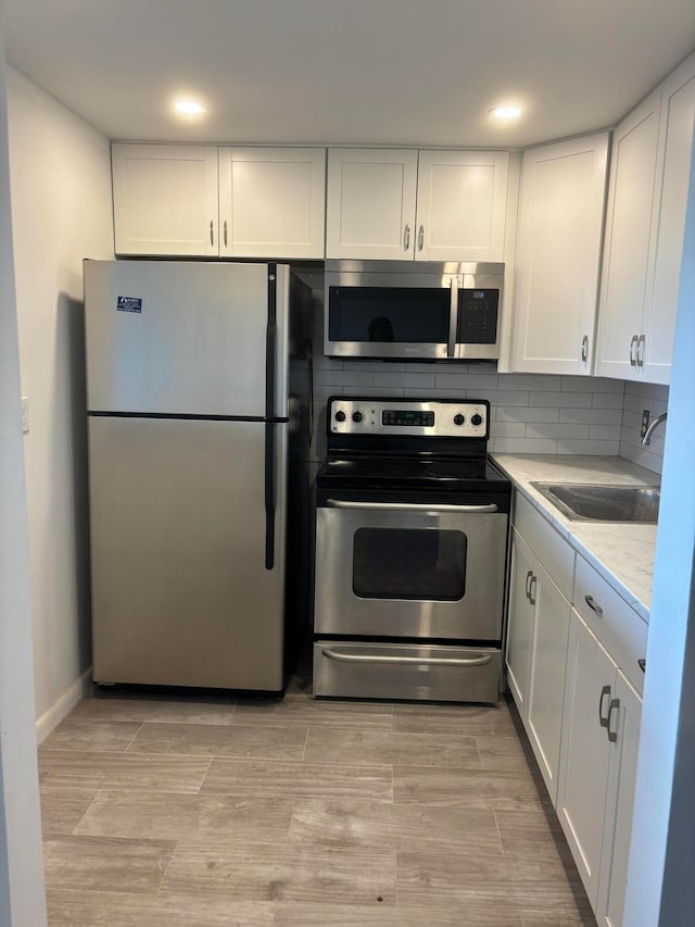 kitchen with white cabinetry, light hardwood / wood-style flooring, stainless steel appliances, and sink